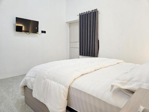 a bedroom with a bed with a tv on the wall at Dhoriz Homestay Syariah RedPartner at Kampung Inggris Pare in Pare