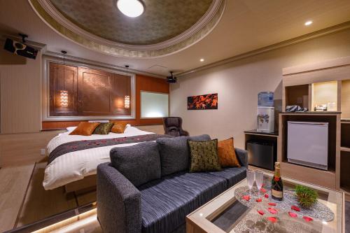 a bedroom with a bed and a couch and a tv at Hotel SWEET SEASON埼玉川越桜の川店 in Kawagoe
