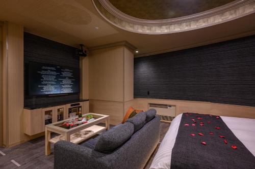 a room with a tv and a couch and a table at Hotel SWEET SEASON埼玉川越桜の川店 in Kawagoe