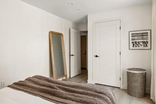 a white bedroom with a bed and a mirror at Tide House - Unit D - Modern Oceanview 1BD w Parking in El Segundo