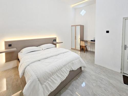 a white bedroom with a large bed with white sheets at Dhoriz Homestay Syariah RedPartner at Kampung Inggris Pare in Pare