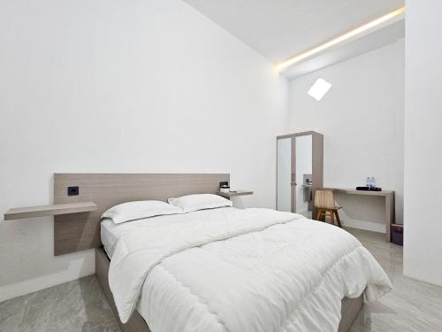 a white bedroom with a large bed and a desk at Dhoriz Homestay Syariah RedPartner at Kampung Inggris Pare in Pare