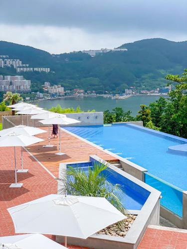 a swimming pool with umbrellas and a view of the water at Hotel SANG SANG & Private SANG SANG POOL VILLA in Geoje 