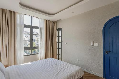 a bedroom with a bed with a blue door and a window at Holiday Villa Novaworld Phan Thiet in Phan Thiet
