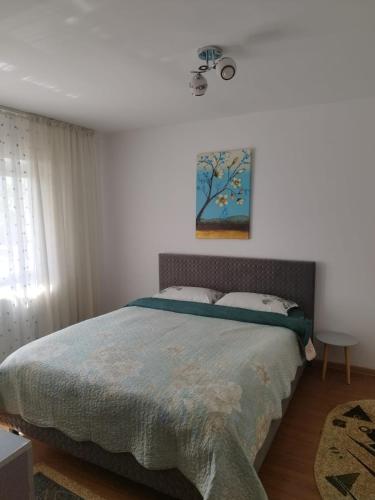 a bedroom with a bed and a painting on the wall at Apartament Miruna in Moineşti
