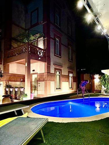 a swimming pool in front of a building at night at Maison Belle Époque & suites in Oristano