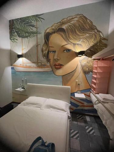 a bedroom with a painting of a woman on the wall at Maison Belle Époque & suites in Oristano