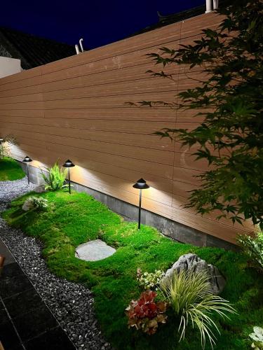 a garden with a wooden wall with lights on it at Da Li Yuan Lu Hotel in Dali Ancient Town
