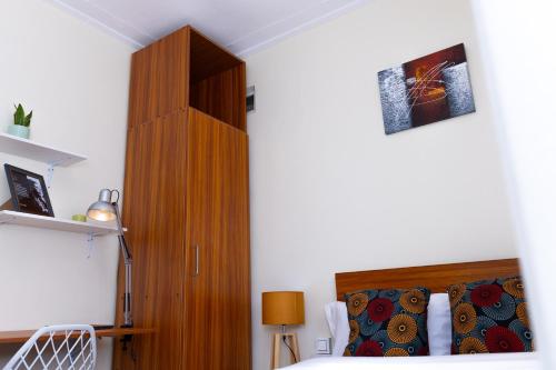 a bedroom with a bed and a wooden cabinet at Kara Space BnB in Kampala