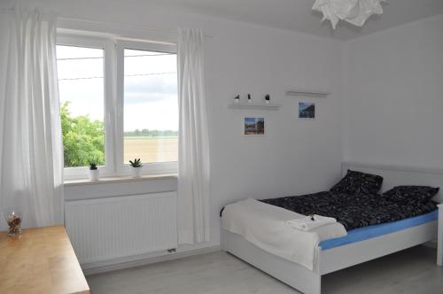 a white bedroom with a bed and a window at Apartament Scorpion Modlin in Czosnów