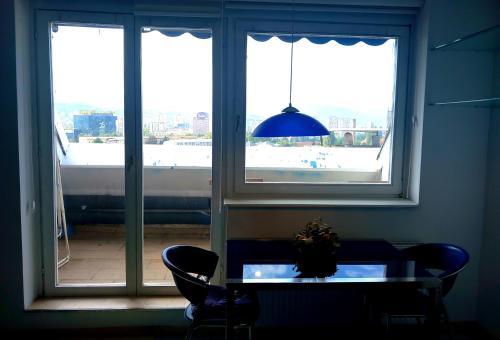 a dining room with a table and two windows at stan/apartman s pogledom in Sarajevo