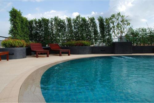a swimming pool with two red chairs next to it at Olive Hotel & Residence Bangkok Sukhumvit 101 in Bangkok