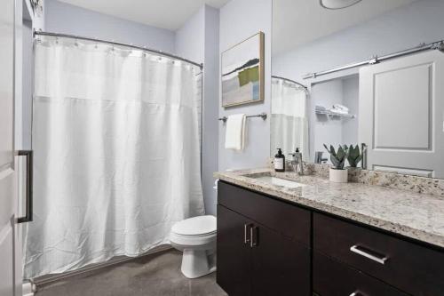 a bathroom with a white shower curtain and a toilet at CozySuites l Dream 1BR, Monument Circle, Indy in Indianapolis