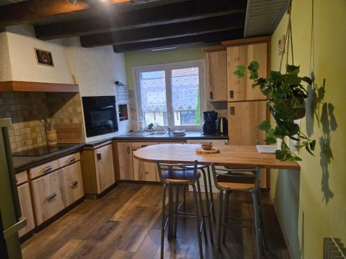 a kitchen with wooden cabinets and a wooden table with stools at Gîte Le Lac à La Dame in Foncine-le-Bas