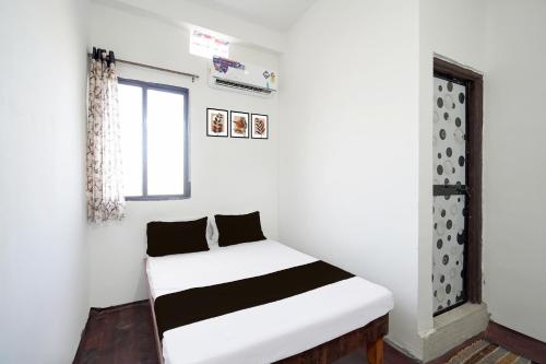 a bedroom with a white bed with black pillows at SPOT ON Ap Logde in Māharjhari