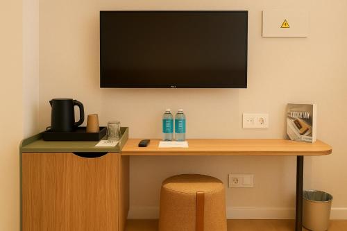 a desk with a flat screen tv on a wall at Petit Palace Puerta del Sol in Madrid