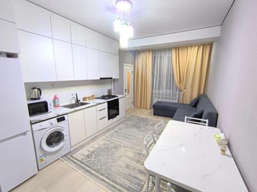 a kitchen and living room with a table and a couch at Квартира в новом доме недалеко от центра Бишкека in Bishkek