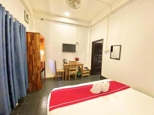 a bedroom with a bed with a red blanket and a table at Villa That Luang Legend in Luang Prabang