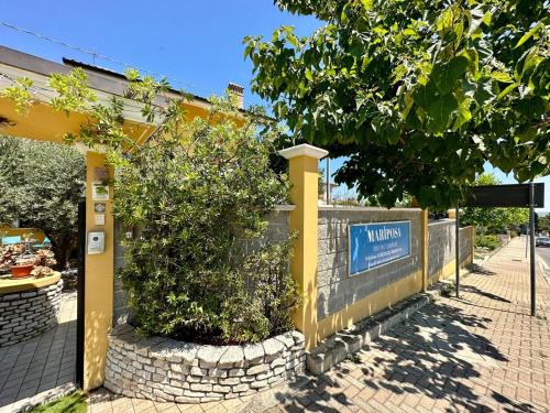 a yellow fence with a tree and a sign at B&B Mariposa in Collecorvino