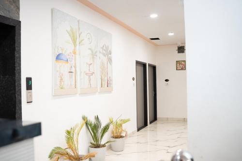 a hallway with potted plants and paintings on the wall at Hotel Enclave Bikaner in Bikaner