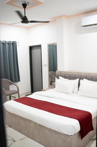 a bedroom with a large bed with a red blanket at Hotel Enclave Bikaner in Bikaner