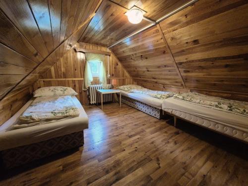 two beds in a room with wooden walls at Chalupa Na hráni in Velká Úpa