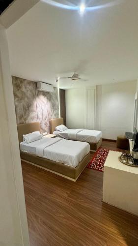 a bedroom with two beds and a painting on the wall at Raidan Suites in Jāmb