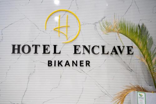 a hotel exchange sign on a wall with a plant at Hotel Enclave Bikaner in Bikaner