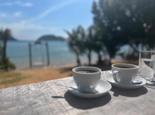 two cups of coffee on a table with a glass of water at Laem Tukkata beach Koh Mak in Ko Mak