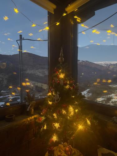 a christmas tree in a room with a window at Mountain house in Palaios Agios Athanasios