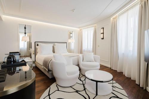 a white bedroom with a bed and chairs and a table at Lisbon Chiado Hotel & Spa in Lisbon