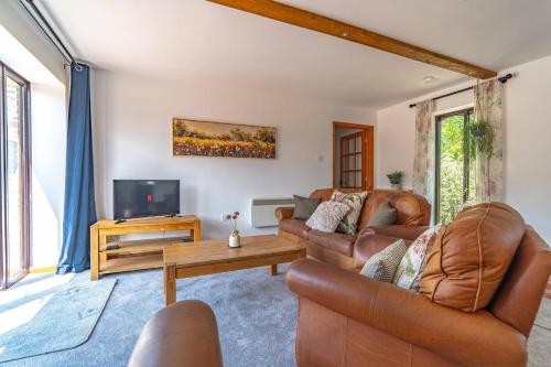 a living room with leather furniture and a tv at Rural Farm Cottage nr Canterbury - logburner, parking, 2bed and 2bath -idyllic setting in Stelling