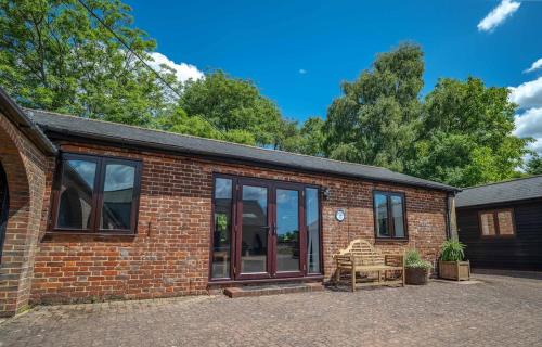 a brick house with glass doors and a patio at Rural Farm Cottage nr Canterbury - logburner, parking, 2bed and 2bath -idyllic setting in Stelling