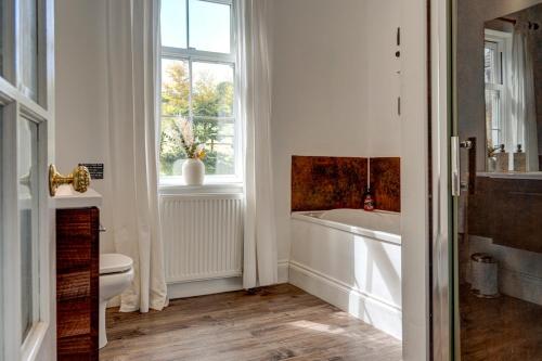 a bathroom with a tub and a toilet and a window at Lambourn House, Countryside Retreat for up to 26 in Lambourn