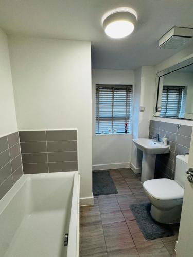 a bathroom with a tub and a toilet and a sink at Cozy Stays Taunton in Norton Fitzwarren