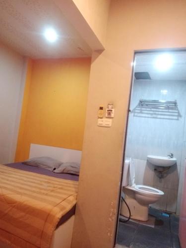 a bathroom with a bed and a sink and a toilet at Hotel Alfatih Banda Aceh in Banda Aceh