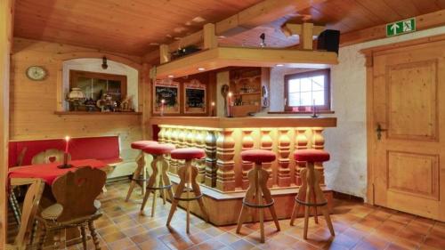 a kitchen with a bar with stools and a table at Hotel Alp Inn - Chiemgaukarte inclusive in Ruhpolding