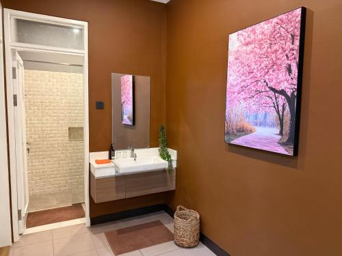 バンドンにあるThe Sakura House - Casa 99 Bandungの洗面台付きのバスルーム、壁に絵画