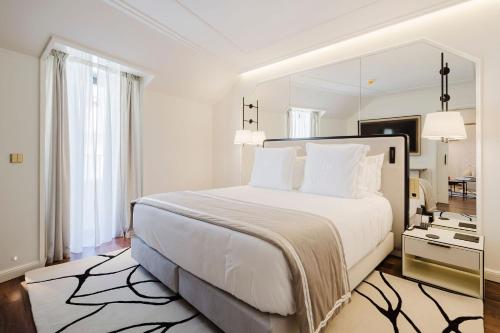 a white bedroom with a large bed and a mirror at Lisbon Chiado Hotel & Spa in Lisbon