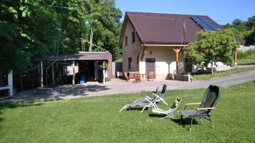 two chairs sitting in the grass in front of a house at Chata dobrý pocit in Horné Orešany