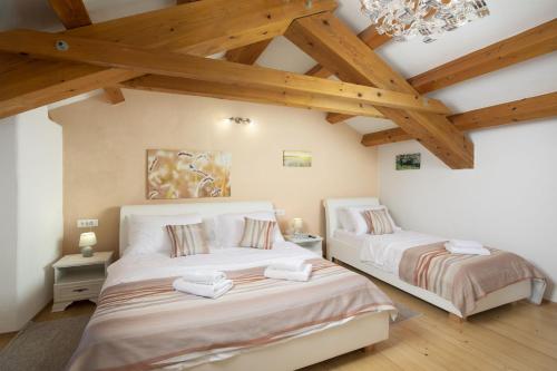 two beds in a room with wooden ceilings at Holiday house Katarina in Barban