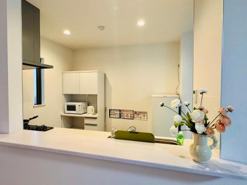 a kitchen with a vase of flowers on a counter at 大阪りんくん新築Yutori蘭 in Izumi-Sano