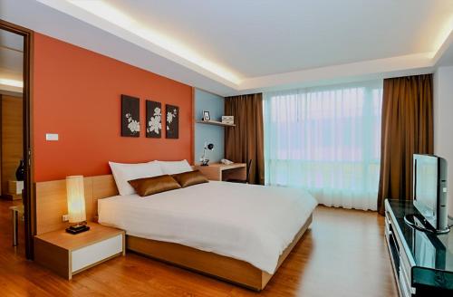 a bedroom with a large bed and a television at Olive Hotel & Residence Bangkok Sukhumvit 101 in Bangkok