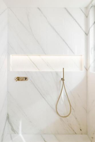 a bathroom with white marble walls and a gold hook at Lisbon Chiado Hotel & Spa in Lisbon