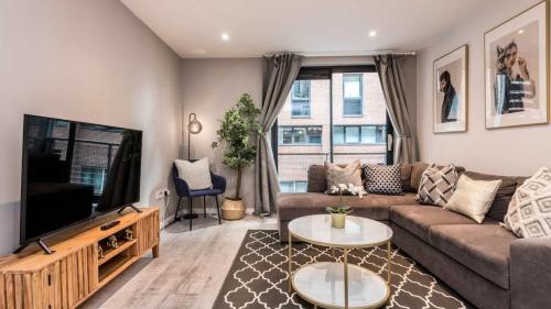 a living room with a couch and a flat screen tv at Stylish Liverpool Apartment with Parking & Balcony in Liverpool