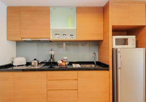 a kitchen with wooden cabinets and a white refrigerator at Olive Hotel & Residence Bangkok Sukhumvit 101 in Bangkok
