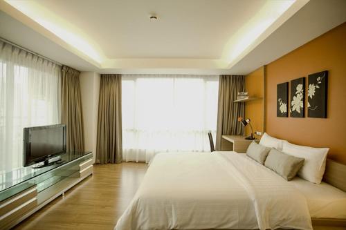 a bedroom with a large bed and a television at Olive Hotel & Residence Bangkok Sukhumvit 101 in Bangkok