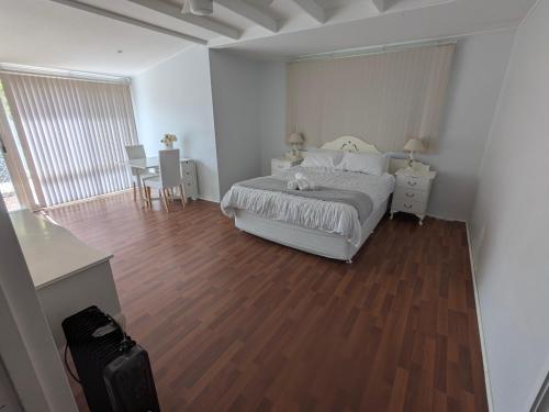 une chambre blanche avec un lit et un parquet dans l'établissement The Cottage on George Street, à Jarrahdale