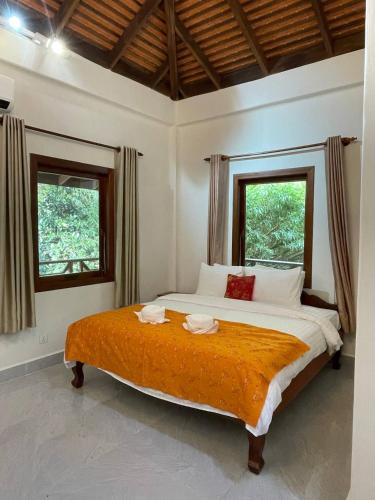 a bedroom with a large bed with two windows at Villa Kep Sea & Mountains in Phumĭ Ŏng Char