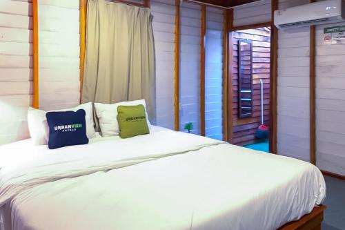 a bedroom with a white bed with two pillows at Urbanview Onengan Resort in Palang-Putih